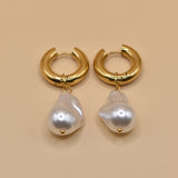 Gold huggies earrings with pearl drop on white background