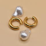 Gold huggies earrings with pearl drop on white background