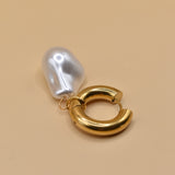 Gold huggies earrings with pearl drop on white background